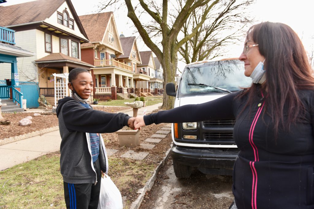 Laura Manriquez, known to her neighbors as “Milwaukee’s Food Fairy,” frequently delivers food from food pantries and stores to those with transportation issues. Here, she fist bumps DelMonte, her Lincoln Village neighbor and mentee. Photo by Sue Vliet/NNS.
