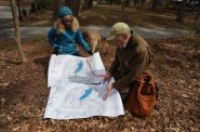 Belle Ragins and Erik Thelen, who live near the site of Kohler Co.’s proposed golf course in Sheboygan, Wis., examine a map prepared by environmental engineer Roger Miller, who chairs the town of Wilson Plan Commission. The map overlays the project with present lake levels, showing several planned features under water due to erosion and fluctuating water levels along Lake Michigan’s shoreline. Photo taken April 27, 2021. Credit: Dee J. Hall / Wisconsin Watch