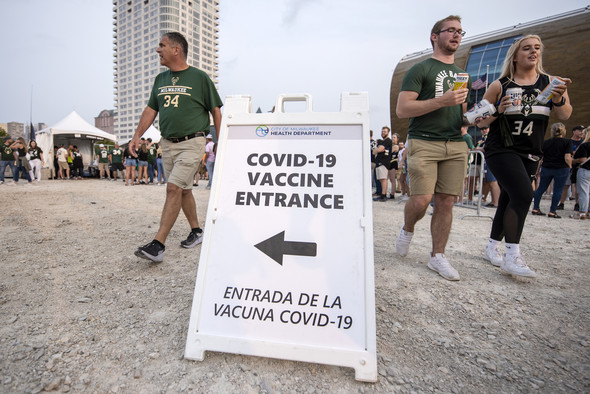 Fans walk past a sign advertising COVID-19 vaccines Tuesday, July 20, 2021, outside the Fiserv Forum in Milwaukee, Wis. Angela Major/WPR