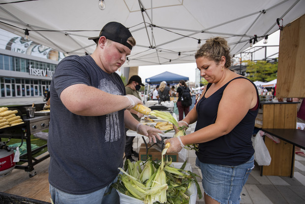 Clayton Morgan, left, and Heidi Herro, right, shuck corn for sale at Sweet Caroline Roasted Corn on Wednesday, July 28, 2021, at the Deer District in Milwaukee, Wis. Angela Major/WPR