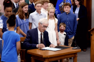 Gov. Tony Evers signs the 2021-23 biennial budget at Cumberland Elementary School in Whitefish Bay, after making 50 partial vetoes. Screenshot from Gov. Evers Facebook video/Wisconsin Examiner.