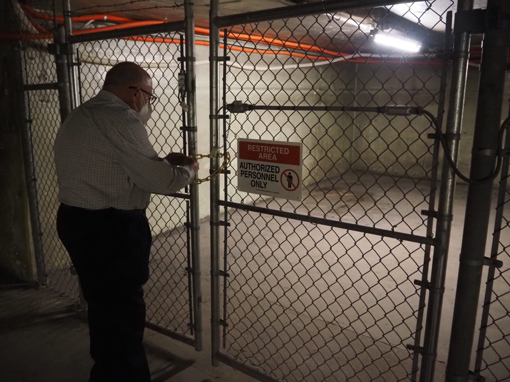 Sam Denny locks a gate to a tunnel in the Schlitz Park complex. Photo by Jeramey Jannene.