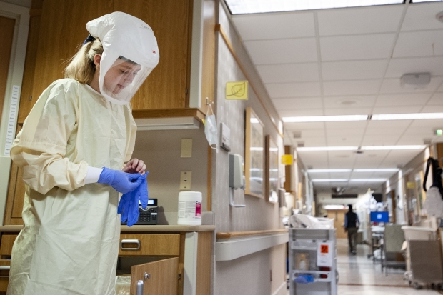 nurse puts on gloves before entering a COVID-19 patient’s room Tuesday, Nov. 17, 2020 at UW Hospital. Angela Major/WPR