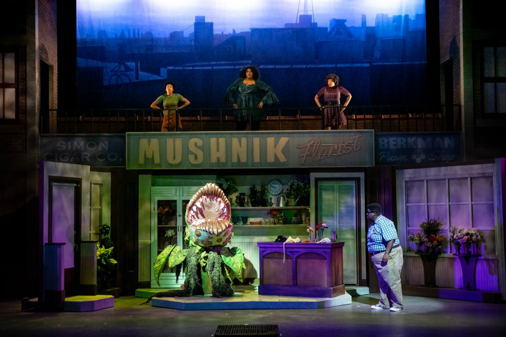 (l. to r.) Kristen Jeter (Chiffon), Raven Dockery (Ronnette), Brandite Reed (Crystal), and Kevin James Sievert (Seymour) in Skylight Music Theatre’s production of Little Shop of Horrors running November 19, 2021 - January 2, 2022. (Editor’s Note: Audrey II Puppeteer - Gabriella Ashlin. Audrey II Voice - Aaron Reese Boseman). Photo by Mark Frohna.