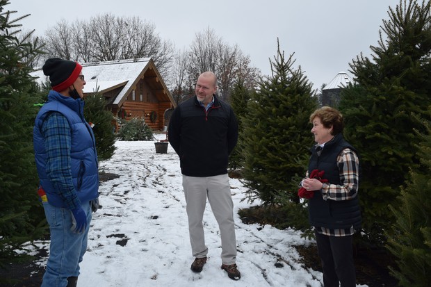Randy Romanski, secretary of the Wisconsin Department of Agriculture, Trade and Consumer Protection, center, talks with Tim and Therese Olson on their Christmas tree farm in Eleva, Wis. on Friday, Dec. 3, 2021. Hope Kirwan/WPR