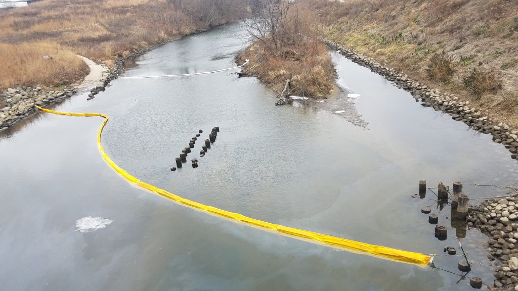 Oil from Komatsu's spill goes around a boom in the Menomonee River. Photo from Ediquelson Camara.