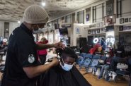 Milwaukee native Antonio Perkins, left, trims a client’s hair Tuesday, Feb. 8, 2022, at Gee’s Clippers, a barber shop in Milwaukee, Wis. Angela Major/WPR