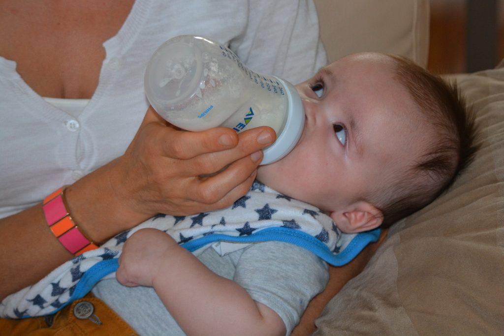 A baby drinks from a bottle. (Pixabay license).
