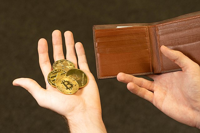 Cryptocurrency Medallions Alongside Wallet. Photo by CryptoWallet.com Images, CC BY 2.0 , via Wikimedia Commons