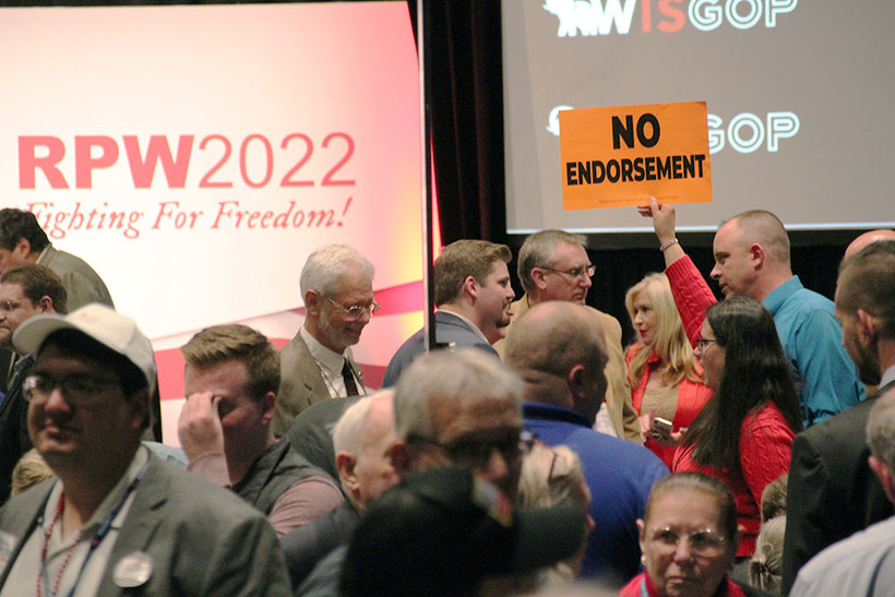 A woman holds up a "NO ENDORSEMENT" sign at the 2022 Wisconsin Republican Party Convention. Shawn Johnson/WPR