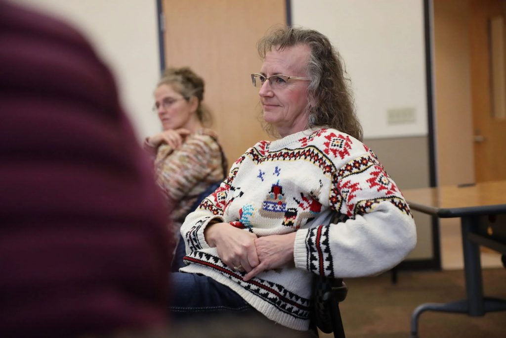 Alicia Cashman leads a meeting of the Madison Area Lyme Support Group at the East Madison Police Station in Madison, Wis., on Feb. 8, 2020. About 13 other people were in attendance, some of whom had driven from more than an hour away. The group shared personal experiences with chronic Lyme disease. Also pictured is Olivia Parry of Madison, Wis. (Coburn Dukehart / Wisconsin Watch)