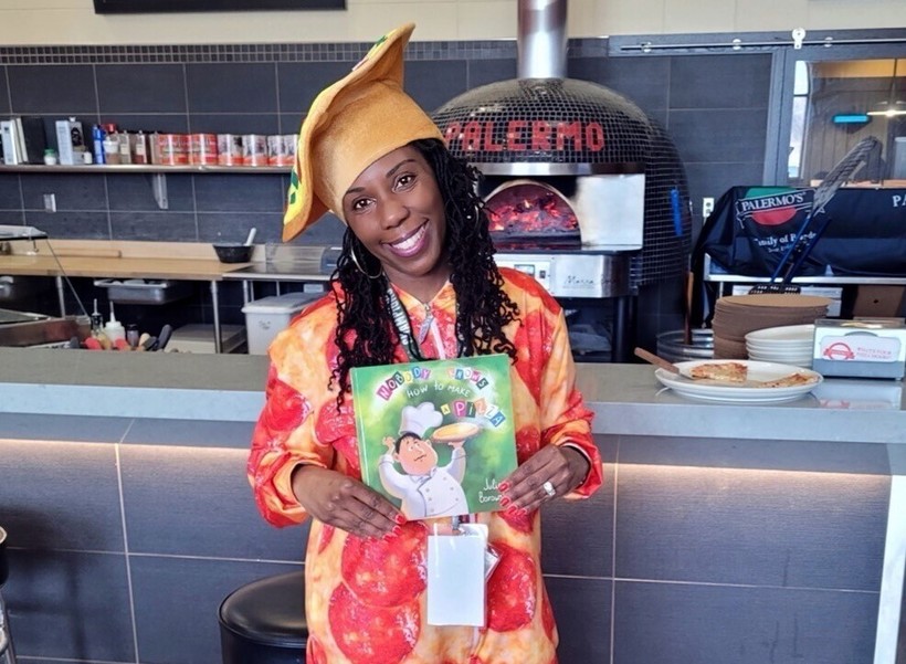 Dannette Justus, a literacy coach with Milwaukee Public Schools, has a video series called "JustUs and Books," where she reads books at places throughout Wisconsin, including at a Palermo's Pizza location in April. Photo courtesy of Dannette Justus/WPR.