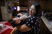 Raquel Urbina feeds her daughter Adaliz Angeles on June 24, 2022 at their home in Milwaukee. Urbina is an administrator of the Milwaukee Formula Parents Facebook group, which allows its 3,000-plus members to swap tips about how to obtain baby formula during a national shortage in recent months. Searching for formula feels like a “treasure hunt,” Urbina says. (Coburn Dukehart / Wisconsin Watch)