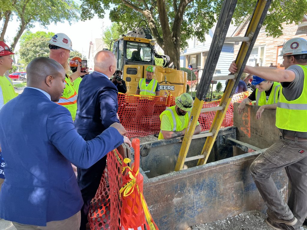 Mayor Cavalier Johnson (left) and infrastructure coordinator Mitch Landrieu (center) look at a lead service line replacement. Photo by Jeramey Jannene.
