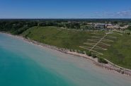 In 2007, the Concordia University Wisconsin, in Mequon, Wis., finished fortifying a 130-foot bluff and building a 2,700-foot-long rock wall to buffer waves. The $12 million project was among the largest built along Lake Michigan in Wisconsin. Neighboring landowners soon noticed changes to their property. The project has accelerated erosion on downstream properties from around 9 inches to more than 7 feet per year. After two couples sued, a jury later agreed that Concordia’s construction caused “significant harm” to properties, but the university was not negligent. The jury awarded no damages, leaving bitterness over the seawall to linger in the neighborhood Photo taken Aug. 9, 2022. (Coburn Dukehart / Wisconsin Watch)