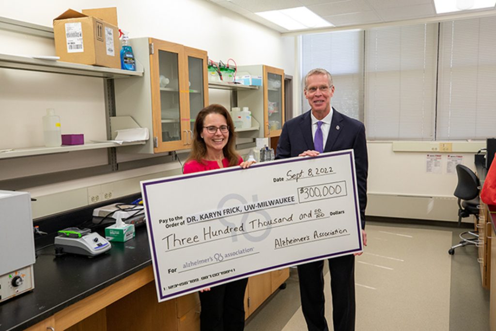 Karyn Frick, a distinguished professor of psychology at UWM, and David Grams, executive director of the Alzheimer's Association Wisconsin Chapter, hold a giant check reflecting the amount of a research grant. (UWM Photo Services/Troye Fox)