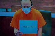 Darrell Brooks Jr. is shown on a monitor in the media room of the courthouse holding up a sign that says, "objection." Evan Casey/WPR