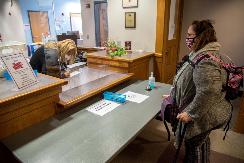 Lee Ann Medina, right, looks on as a Milwaukee Elections Commission employee witnesses her absentee ballot on the day of the election on August 11, 2020. (Will Cioci / Wisconsin Watch)