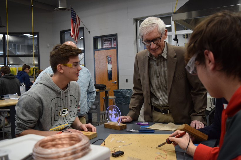 Gov. Tony Evers talks with Caden Monty, left, and Alex Ramussen, both 9th grade students at Holmen High School on Monday, March 13, 2023. Evers visited the school to promote his universal school meal proposal for the next state budget. Hope Kirwan/Wisconsin Public Radio