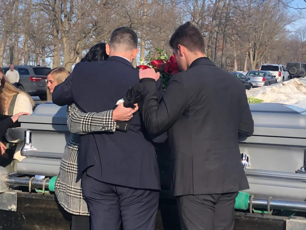 Erin and Rick Rachwal and their son Caden mourn at the funeral of their son and brother, Logan Rachwal. The family launched a foundation to warn of the dangers of opioids after Logan was poisoned by a pain pill laced with fentanyl on Feb. 14, 2021. (Courtesy of the Rachwal family)