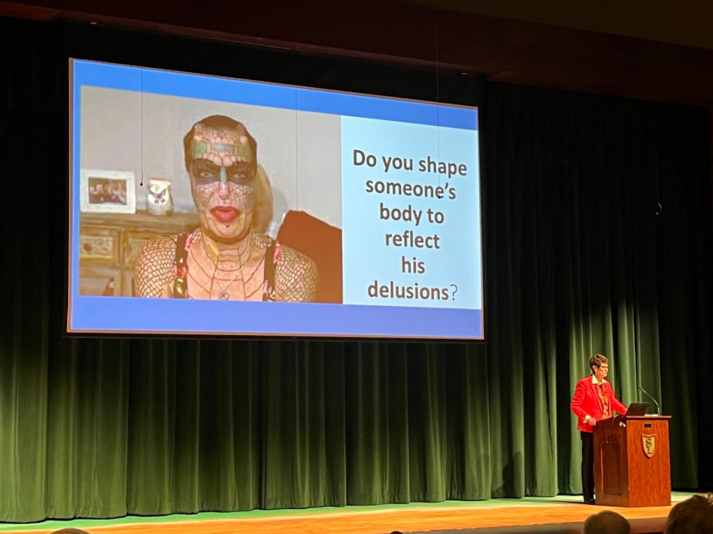 At an April 19, 2023 talk at Sheboygan Lutheran High School, Christian clinical psychologist Beverly Yahnke described being transgender as a “delusion,” displaying an image of the transgender body-modification artist Tiamat Legion Medusa, whom she misgendered, to make her point. “We don’t treat delusions with scalpels. We treat delusions with psychiatric care,” Yahnke said. Transition-related care, which only sometimes includes surgeries, is endorsed by every major medical association. (Phoebe Petrovic / Wisconsin Watch)