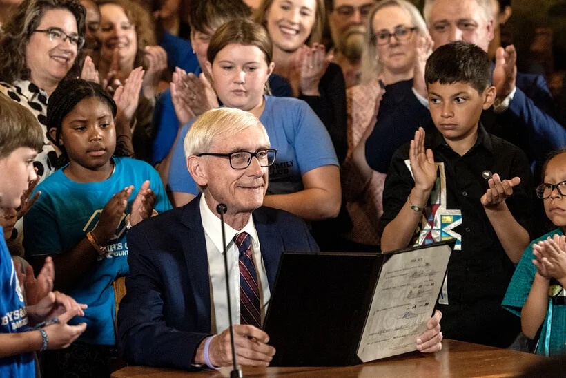 Gov. Tony Evers smiles as he holds the freshly signed biennial budget Wednesday, July 5, 2023, at the Wisconsin State Capitol in Madison, Wis. Angela Major/WPR