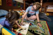 Teacher Morgan Cutler reads books with children after lunch Monday, June 19, 2023, at Red Caboose in Madison, Wis. Angela Major/WPR