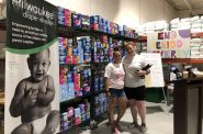 Nicole Dachs (left) and Jamie Robarge, who are volunteers at the Milwaukee Diaper Mission, stand in front of a wall of 15,000 period products they were able to raise at their second annual Period Party. Photo by Trisha Young/NNS.