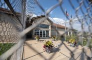 Flags, potted plants and barbed wire fencing can be seen outside Oakhill Correctional Institution on Thursday, Aug. 24, 2023, in Oregon, Wis. Angela Major/WPR