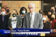Cynthia Brown, second from left in the row behind Gov. Tony Evers, attends a press conference where the Diverse Business Assistance Grant recipients were announced in October 2021 at the Wisconsin State Capitol. Brown’s grant was suspended after the Department of Administration flagged several suspicious uses of $1 million she received last year. (Screen capture courtesy of CBS 58)