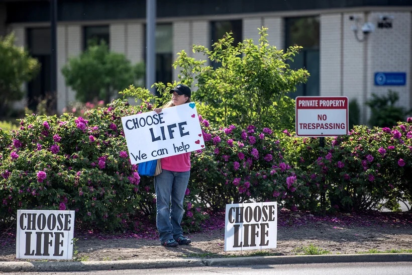 One of three protesters stands with a sign outside of a Planned Parenthood on Wednesday, June 7, 2023, in Waukegan, Ill. Angela Major/WPR