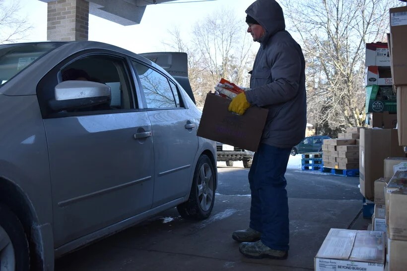 Tim Kapfhamer of St. Bernard's Catholic Church carries a box of food to the car of a social worker who will distribute it to rural families, February 2, 2023. Rob Mentzer/WPR