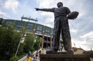 A statue of Curly Lambeau stands tall as fans walk in to Lambeau Field to watch the Green Bay Packers play the New Orleans Saints in a preseason football game Friday, Aug. 19, 2022, in Green Bay, Wis. Angela Major/WPR