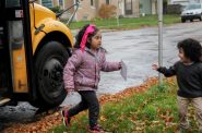 Leonardo Coronado, 3, greets his 6-year-old sister Magaly Coronado as she gets off the bus from school in Milwaukee on Oct. 26, 2023. The buses often run late in returning Magaly home from school, including on a day Wisconsin Watch visited her bus stop. (Jonmaesha Beltran / Wisconsin Watch)