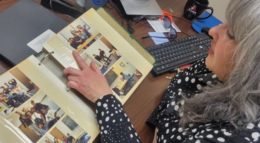 Maria Flores, executive director of New Concept Self Development Center, looks through old photos of teens served by the organization. (Photo by Edgar Mendez)