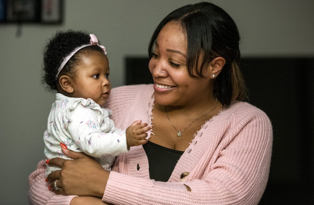 Khola Cooksey holds her daughter Nyla, on Jan. 18, 2022, in Wauwatosa, Wis. The peer counselor splits her time working for the Milwaukee-based African American Breastfeeding Network and Milwaukee’s Women, Infants, and Children program. She considers both workplaces family-friendly, helping her support the mothers she serves. Angela Major/WPR