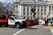 One of a dozen snowplows from across Wisconsin honks in support as it passes demonstrators with signs supporting SB 52 on March 19, 2024 outside the State Capitol. Image from video courtesy Wisconsin Salt Wise.