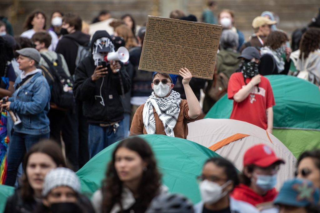 Pro-Palestinian protesters hold signs near the tents in the Library Mall on Monday, April 29, 2024, at the University of Wisconsin-Madison in Madison, Wis. Angela Major/WPR