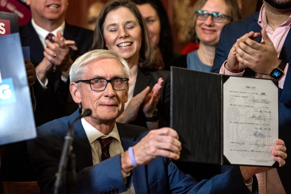 Gov. Tony Evers holds up the bill after signing it Monday, Feb. 19, 2024, at the Wisconsin State Capitol in Madison, Wis. (Angela Major/WPR)