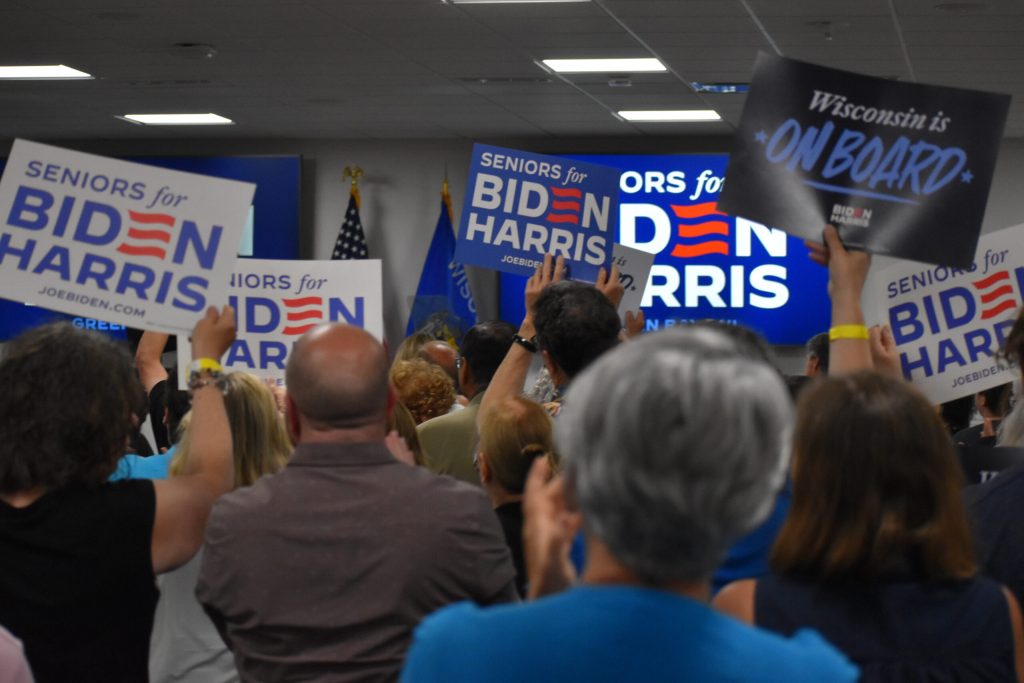 Supporters raise Biden-Harris campaign signs during an event at the Brown County Public Library on Thursday, June 13, 2024. Joe Schulz/WPR