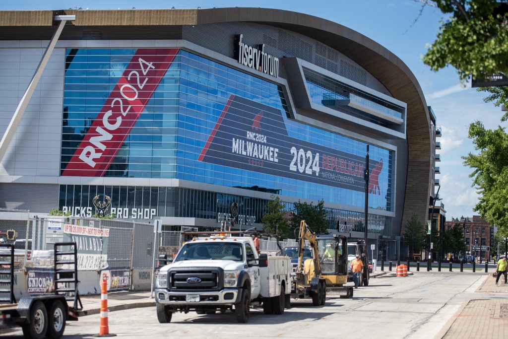 Construction crews work outside Wednesday, July 3, 2024, at the Fiserv Forum in Milwaukee, Wis. The venue is covered in signs for the upcoming Republican National Convention. Angela Major/WPR