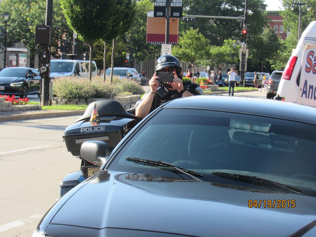 An officer films a protest during the march and rally for Sam Sharpe and Dyvontaye Mitchell. (Photo | Isiah Holmes)