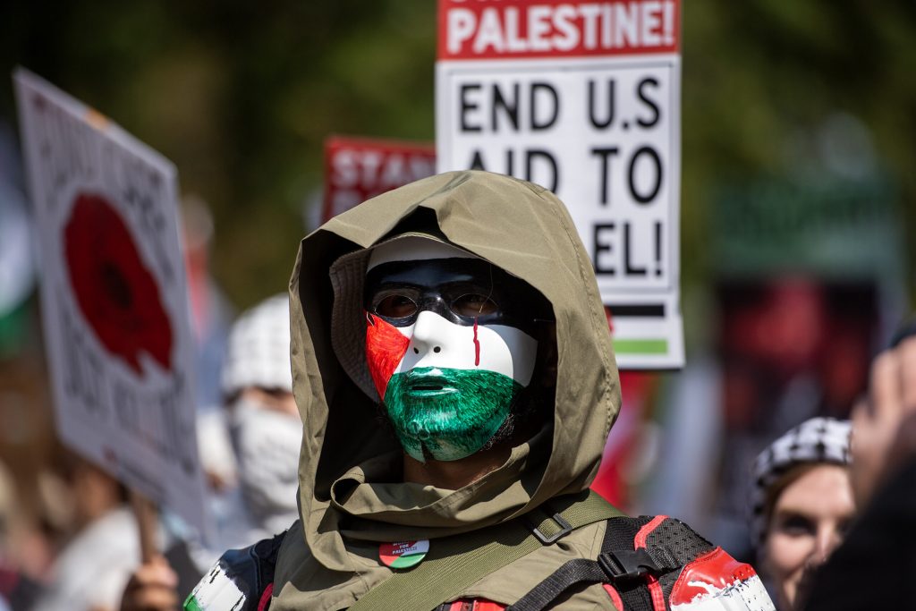 A protester wears a mask while standing at the front of the march during a pro-Palestinian protest in response to the Democratic National Convention on Monday, Aug. 19, 2024, in Chicago, Ill. Angela Major/WPR