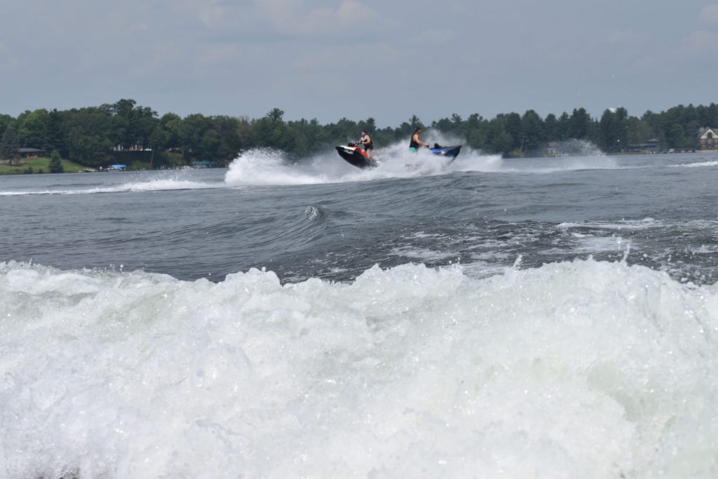 Jet skiers are riding and jumping waves created by a wake boat on Lake Minocqua on July 22, 2024. Danielle Kaeding/WPR