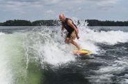 Waves created by a wake boat crash against Mike Scandin as he wake surfs on Lake Minocqua on July 22, 2024. Danielle Kaeding/WPR