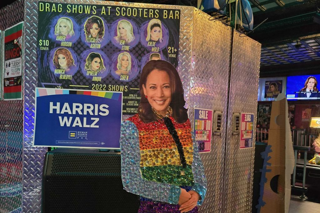 Democrats at a Sept. 10 presidential debate watch party at Scooters bar in Eau Claire took turns taking selfies with a cardboard cutout of Vice President Kamala Harris adorned with a rainbow colored jacket and sequins. Rich Kremer/WPR