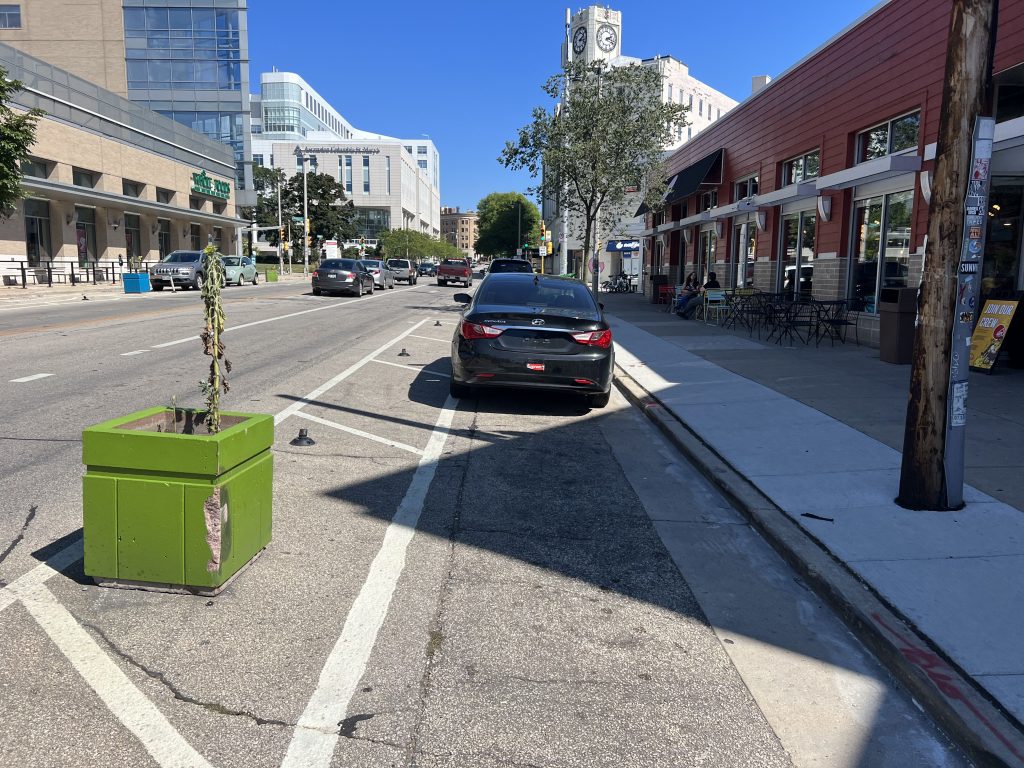 Drivers illegally parked in the damaged protected bike lane in September 2024. Photo by Jeramey Jannene.