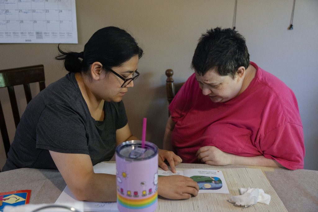 Rosa Landa, owner of Good Hand Care AFH assisted living facility, left, reads a book with Bebette Gaus on Aug. 23, 2024, in Madison, Wis. Gaus has lived at the facility for three years. (Joe Timmerman / Wisconsin Watch)