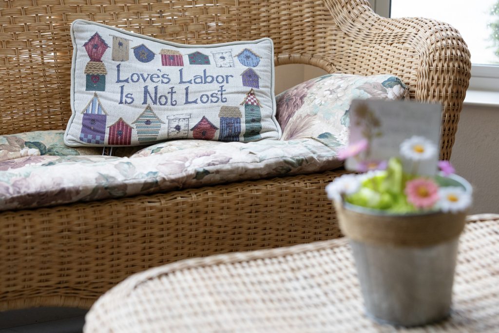 Pillows and flowers decorate the sunroom at Marvin’s Manor, an assisted living facility in Horicon, Wis., on Aug. 15, 2024. (Joe Timmerman / Wisconsin Watch)