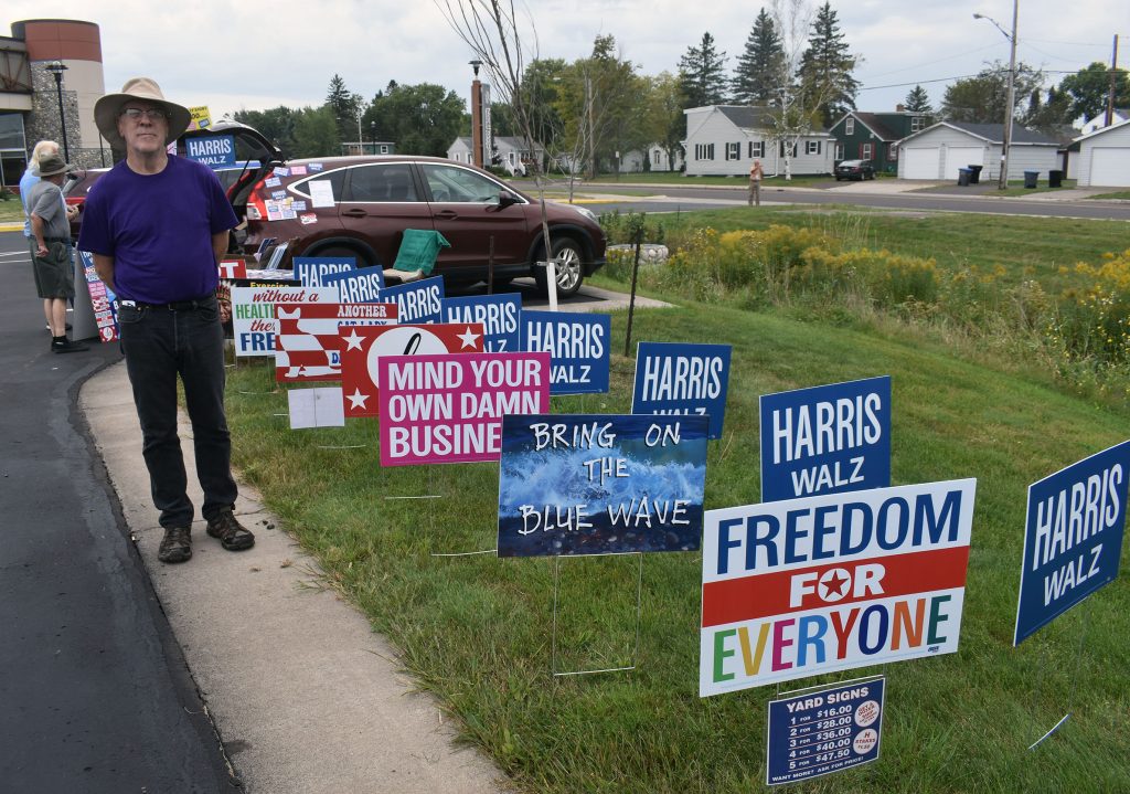 Ashland resident and business owner Will Pipkin displayed signs outside the Walz rally on Sept. 14, 2024. Pipkin said climate change and support for the LGBTQ+ community are among his top issues, adding he likes Walz’s “homespun” values. Danielle Kaeding/WPR